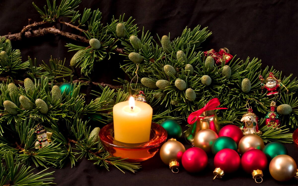 Burning candle among branches with cones and Christmas balls