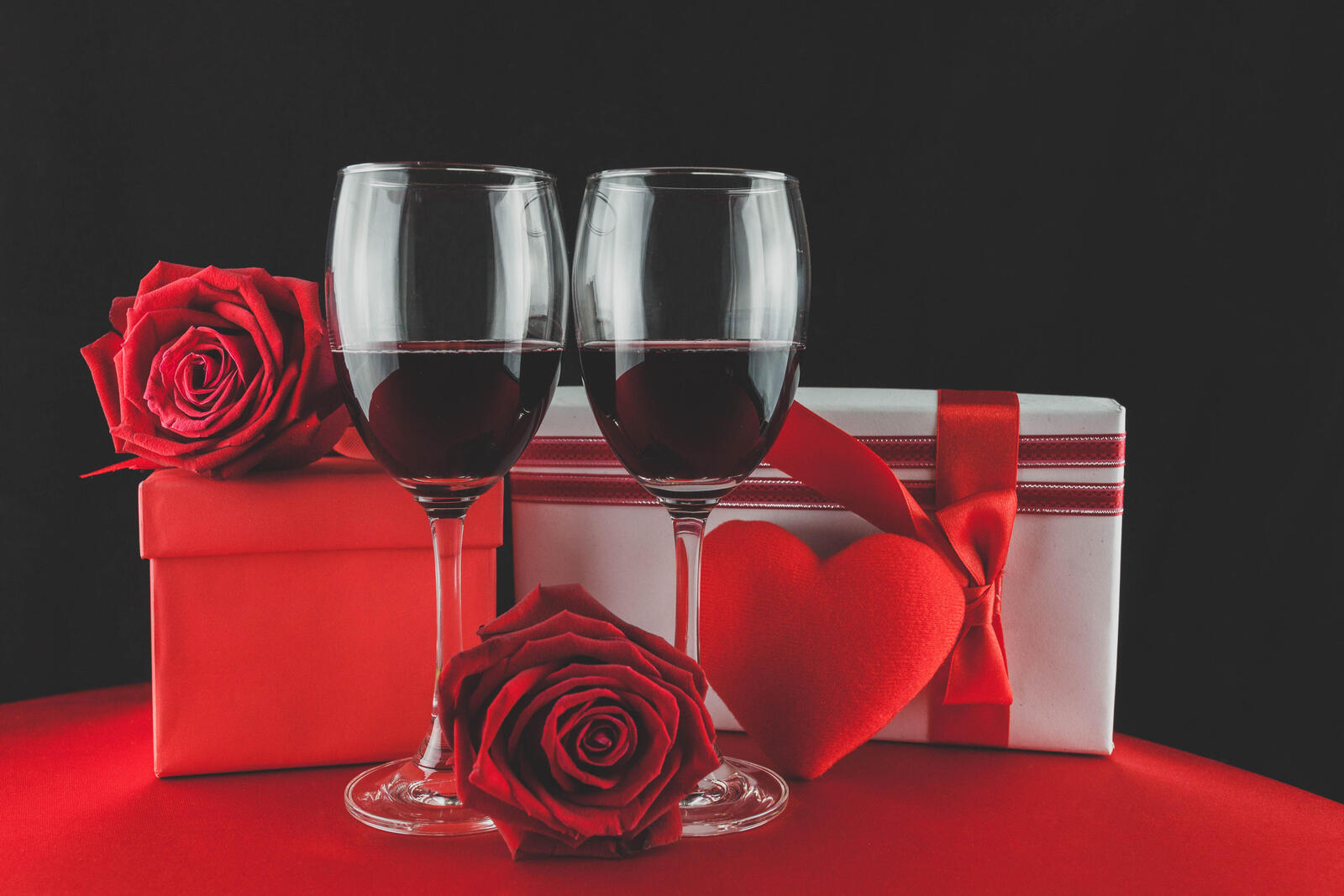 Free photo Two red wine glasses with valentine`s day gifts.