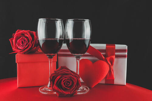 Two red wine glasses with valentine`s day gifts.