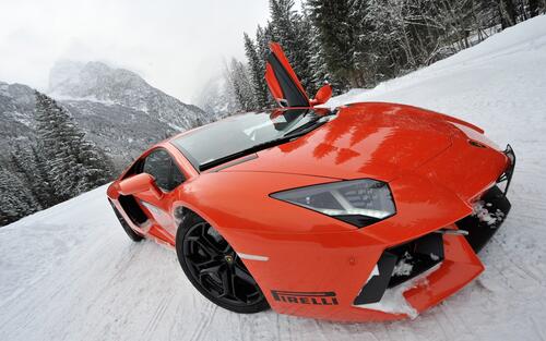 An orange Lamborghini on a snowy road.