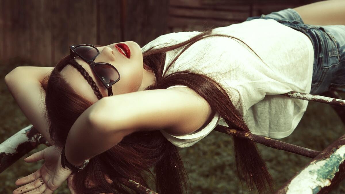 Girl in sunglasses relaxes lying on her back