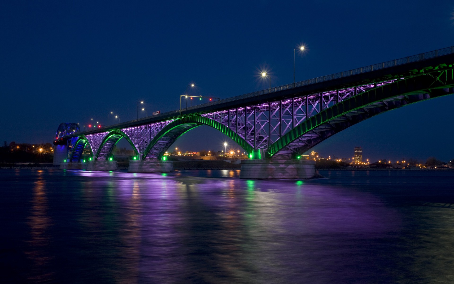 A large illuminated bridge over the river at night