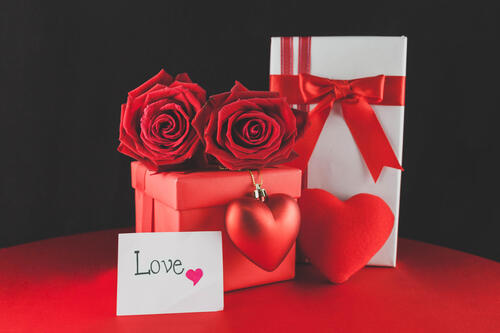 Two red roses with valentine`s day gifts.