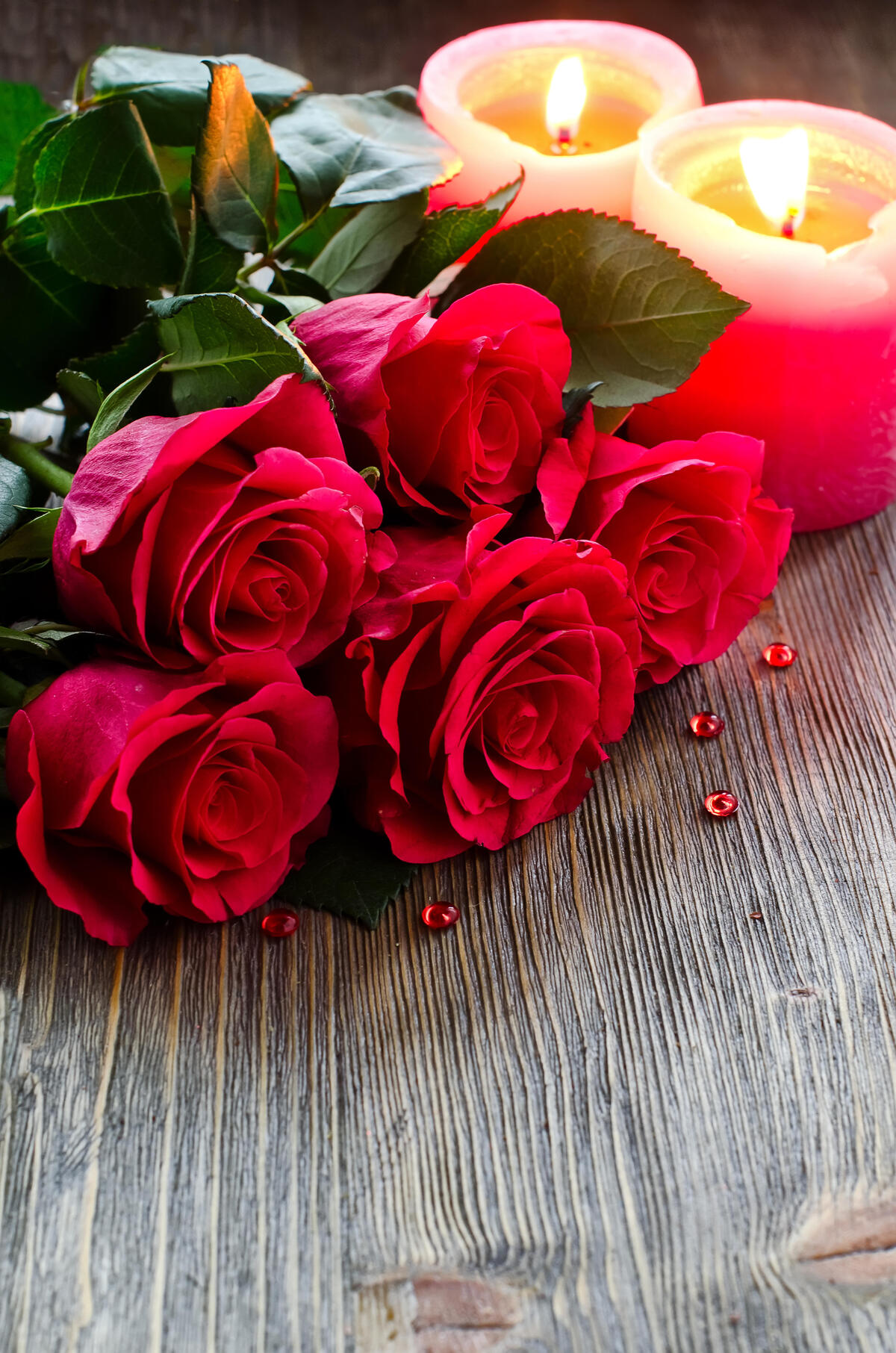 A bouquet of red roses next to burning candles