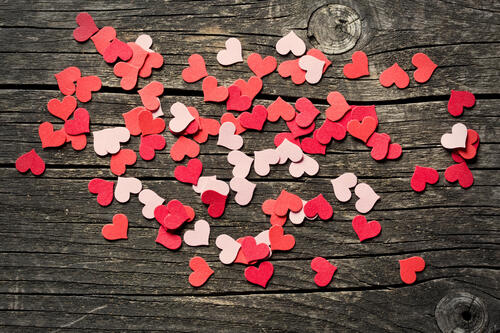 Бумажные сердечки рассыпанные на деревянном столе