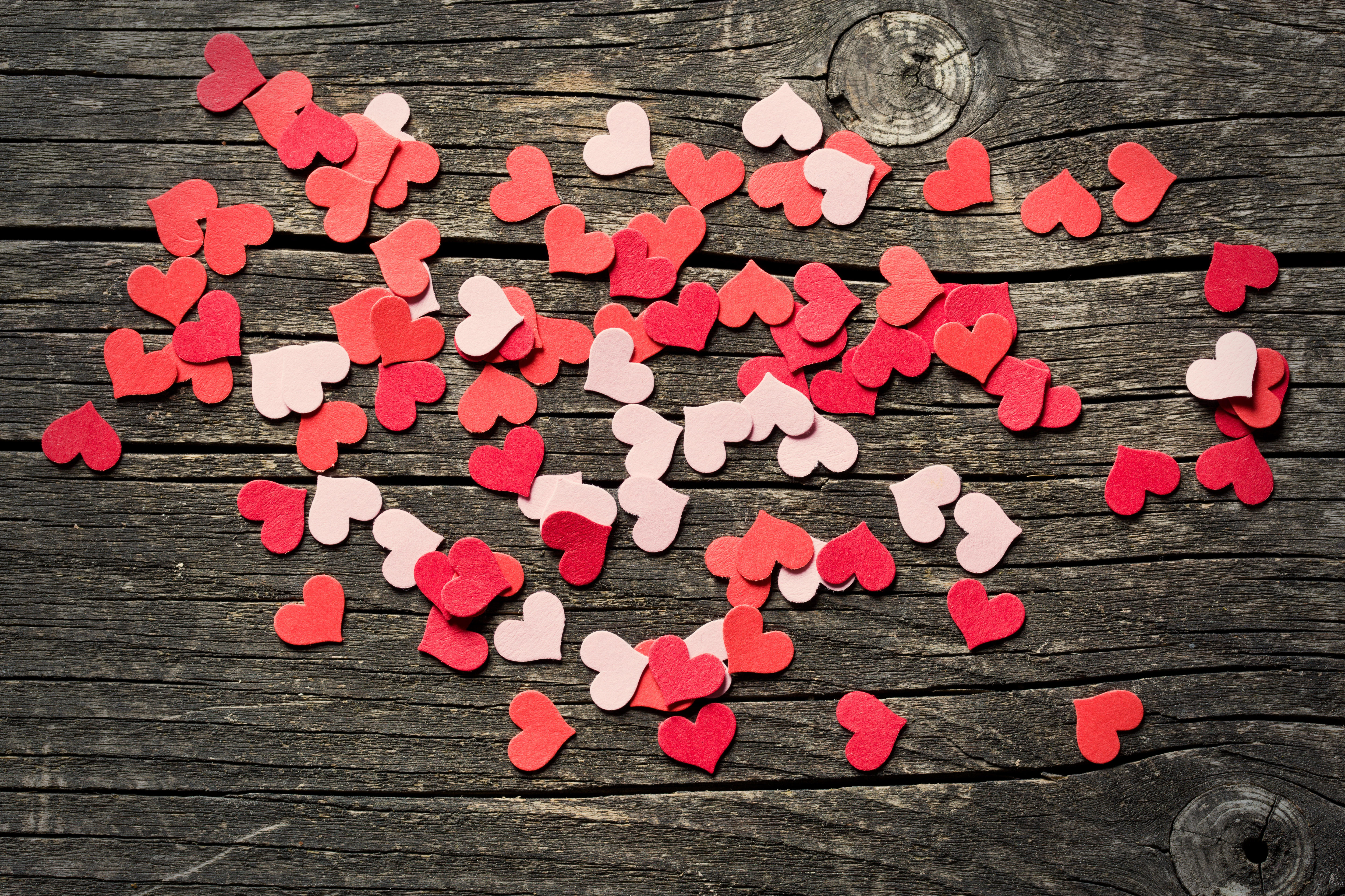 Бесплатное фото Бумажные сердечки рассыпанные на деревянном столе