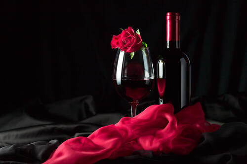 A red wine glass with a red rose.