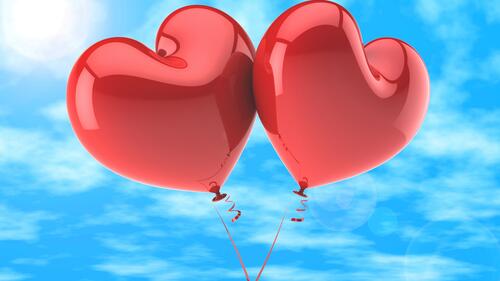 Два воздушных шарика в форме сердца на фоне неба
