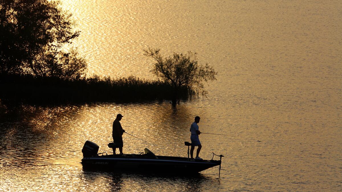 Рыбаки на лодке с удочками в вечернее время