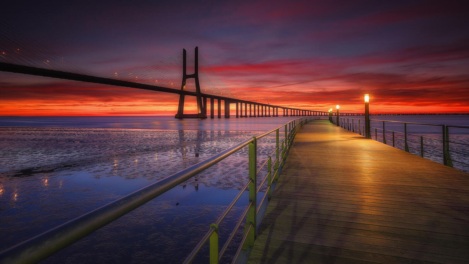Бесплатное фото Длинный мост через реку в Португалии на закате