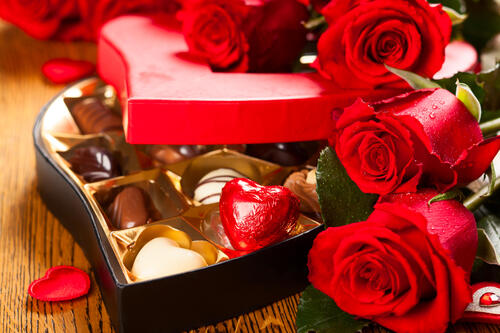 Red roses next to a box of chocolates