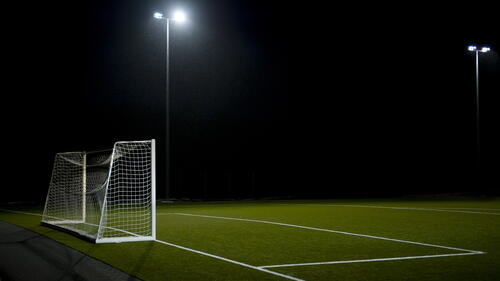 A soccer field in the night under the streetlights